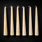 Six beeswax taper candles arranged in a row on a black background.