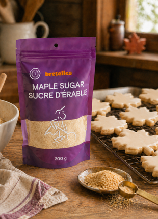 Fine maple sugar pouch beside maple leaf sugar cookies with maple glaze on a rustic kitchen baking counter.