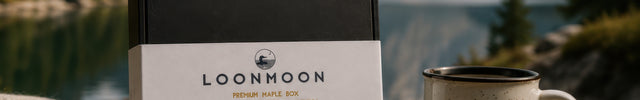 Premium Canadian maple gift box packed by LOONMOON in British Columbia, styled outdoors with a mug, blanket, and mountain lake backdrop.