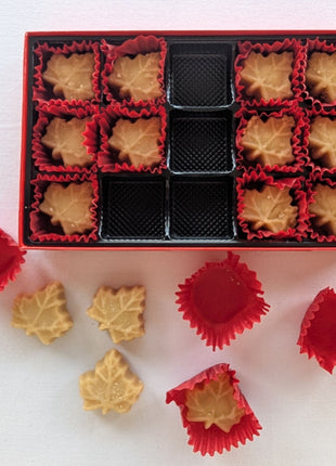 Open Soft Maple Sugar Candy gift box with several maple leaf candies removed from the tray to showcase the individual candies and serving presentation.  Customers can clearly see the soft maple candies, decorative paper cups, and premium gift packaging.