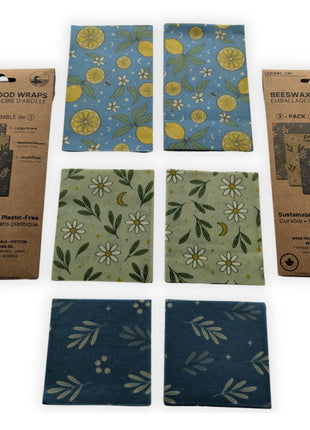 Complete 6-pack reusable beeswax food wraps made in Canada displayed with two retail packages and all six wraps arranged by size and pattern on a white background.  Includes two large, two medium, and two small wraps made from cotton, Canadian beeswax, pine resin, and jojoba oil for sustainable plastic-free food storage, wrapping bread, cheese, fruit, vegetables, and leftovers.