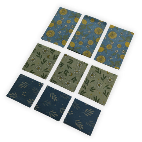 Complete 9-pack reusable beeswax food wraps made in Canada displayed with three retail packages and all nine wraps arranged by size in an angled product presentation on a white background.  Includes three large, three medium, and three small wraps made from cotton, Canadian beeswax, pine resin, and jojoba oil for eco-friendly, reusable food storage that helps reduce single-use plastic in the kitchen.