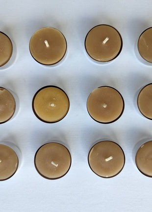 Twelve natural beeswax tealight candles are arranged in a clean three-by-four grid against a white background.  The overhead view clearly shows the full 12-pack, warm honey-gold wax colour, cotton wicks, aluminum cups, and slight handmade variation between individual candles.