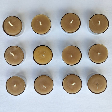Twelve natural beeswax tealight candles are arranged in a clean three-by-four grid against a white background.  The overhead view clearly shows the full 12-pack, warm honey-gold wax colour, cotton wicks, aluminum cups, and slight handmade variation between individual candles.