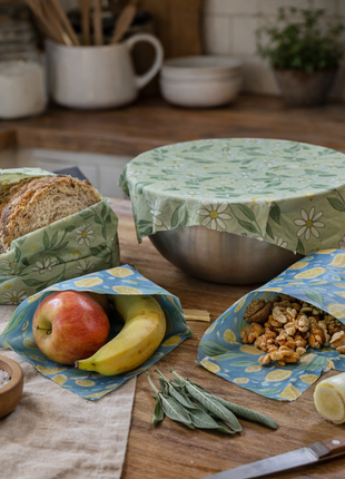 Reusable beeswax food wraps for sustainable kitchen storage, shown wrapping bread, produce, and bowls in a rustic homestead kitchen.
