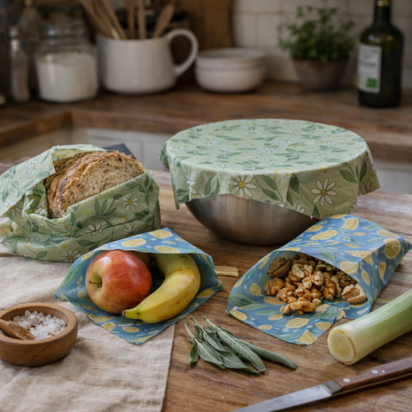 Reusable beeswax food wraps for sustainable kitchen storage, shown wrapping bread, produce, and bowls in a rustic homestead kitchen.