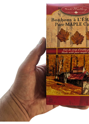 A 100 g package of Canadian hard maple candies held in one hand to show the size and scale of the package. Made in Canada with pure maple syrup, these maple-leaf hard candies offer a portable Canadian maple sweet suitable for gifts, souvenirs and everyday treats.