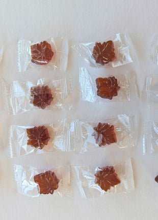 Assortment of individually wrapped Canadian hard maple candies showing the maple-leaf-shaped amber candies through their clear wrappers. Made with pure maple syrup, these Canadian maple candies are individually packaged for convenient sharing, gifting or enjoying one piece at a time.