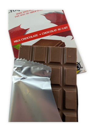 Canadian Maple Crunch milk chocolate bar partially unwrapped to reveal smooth milk chocolate made with pure Canadian maple syrup.  Opening the wrapper showcases the rich milk chocolate and gives customers a closer look at the premium confection inside.