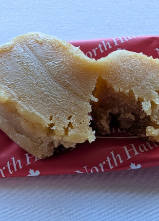 Close-up of a Canadian maple fudge piece broken open to reveal its dense, creamy interior and soft confectionery texture. Made with pure maple syrup, cream and butter, this Canadian-made maple fudge offers a rich maple sweet with a traditional melt-in-the-mouth style.