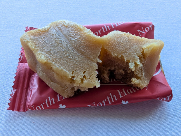 Close-up of a Canadian maple fudge piece broken open to reveal its dense, creamy interior and soft confectionery texture. Made with pure maple syrup, cream and butter, this Canadian-made maple fudge offers a rich maple sweet with a traditional melt-in-the-mouth style.