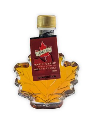 Front view of a 100 ml pure Canadian maple syrup maple leaf bottle with original supplier hang tag attached.   Authentic Canadian maple syrup presented in a classic glass leaf bottle, highlighting premium quality and traditional Canadian maple syrup packaging.
