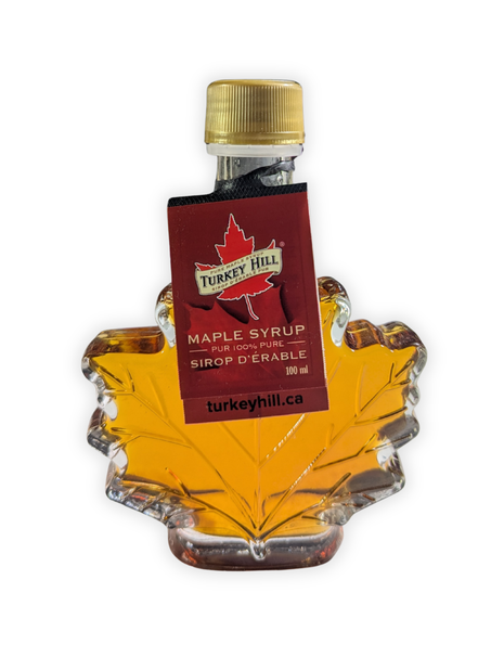Front view of a 100 ml pure Canadian maple syrup maple leaf bottle with original supplier hang tag attached.   Authentic Canadian maple syrup presented in a classic glass leaf bottle, highlighting premium quality and traditional Canadian maple syrup packaging.