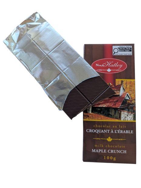 Partially unwrapped Canadian Milk Chocolate Maple Crunch bar showing the segmented chocolate squares beside its package. This 100 g Canadian maple treat combines milk chocolate with maple sugar.