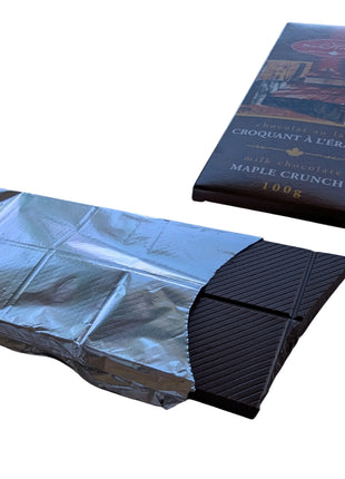 Unwrapped Milk Chocolate Maple Crunch bar displayed with its Canadian maple-themed package, showing the chocolate squares and silver wrapper. A Canadian-made milk chocolate treat featuring maple sugar.