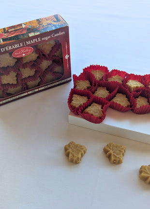 Canadian maple sugar candies displayed beside their 100 g gift box, with individual maple-leaf candies arranged in front. Made in Canada with pure maple syrup, these maple candies make a distinctive Canadian food gift or sweet treat.