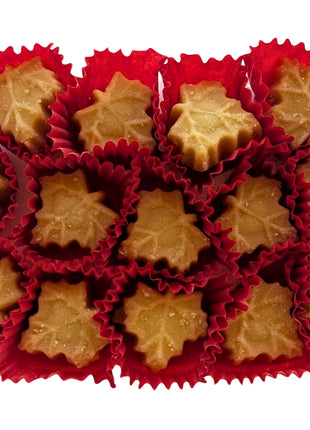 Maple-leaf-shaped Canadian maple sugar candies displayed outside their package in individual red paper cups. Made with pure maple syrup, these traditional Canadian maple candies have a naturally golden maple colour.