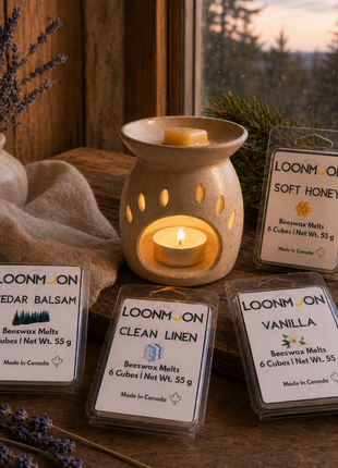 LOONMOON beeswax wax melts in Cedar Balsam, Clean Linen, Soft Honey, and Vanilla beside a glowing ceramic warmer at dusk.