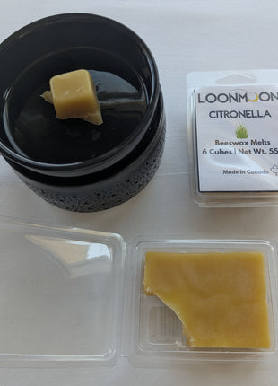 LOONMOON Citronella beeswax melts shown with a black wax warmer, one wax cube in the dish, the closed clamshell package, and the open clamshell revealing the wax inside.  This image helps customers see how the citronella beeswax melts look in use while also showing the product packaging and wax texture.