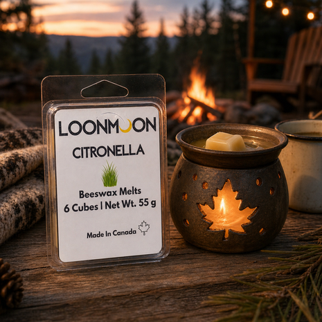 LOONMOON Citronella beeswax wax melts beside a glowing maple leaf warmer on a rustic outdoor picnic table near a campfire.