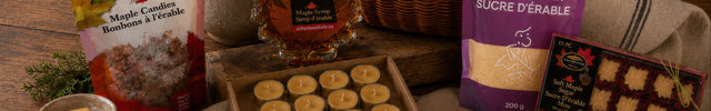 Canadian maple treats, maple syrup, beeswax candles, wax melts, and reusable beeswax wraps arranged on a rustic wooden table.