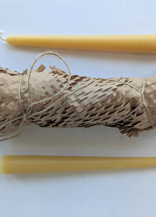 Two natural beeswax taper candles displayed above and below a kraft honeycomb paper-wrapped bundle tied with rustic twine on a clean white background.  This presentation highlights the warm golden colour and gift-ready packaging of the tapers included in the LOONMOON Core Beeswax Candle Gift Box.