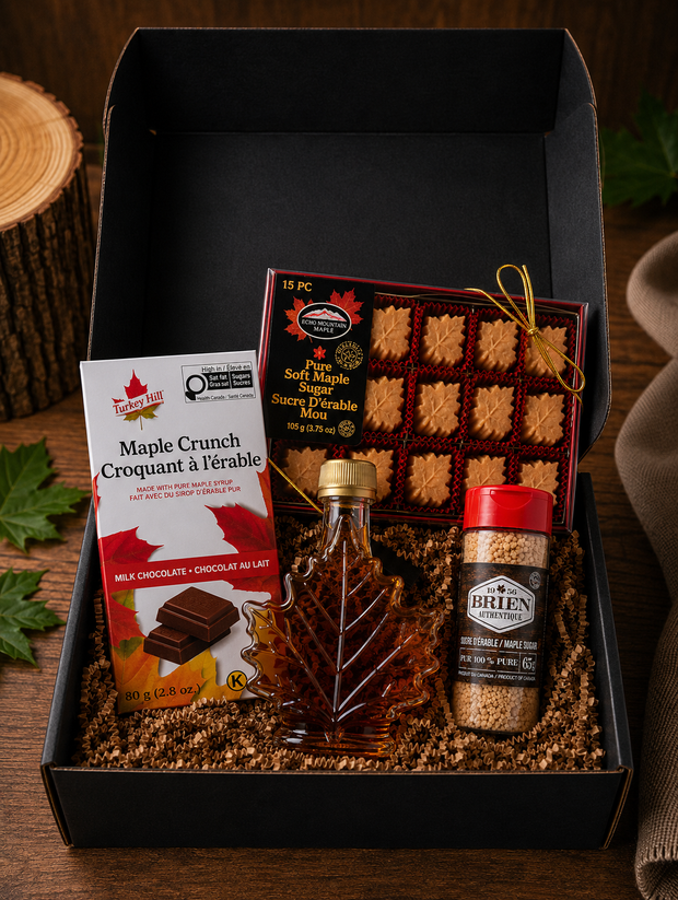 LOONMOON Core Maple Box with Canadian maple treats including maple syrup leaf bottle, soft maple sugar candies, maple sugar shaker, and Maple Crunch Belgian milk chocolate arranged in a black gift box on a rustic wooden table