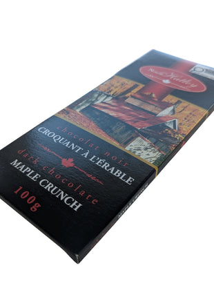 Angled close-up of a Dark Chocolate Maple Crunch package showing its slim chocolate-bar shape and bilingual Canadian packaging. This 100 g Canadian dark chocolate maple treat features maple sugar with dark chocolate.