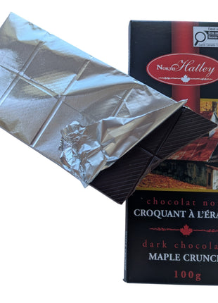 Partially unwrapped Dark Chocolate Maple Crunch bar showing the dark chocolate squares inside the silver wrapper beside the package. A Canadian-made dark chocolate maple treat featuring maple sugar.