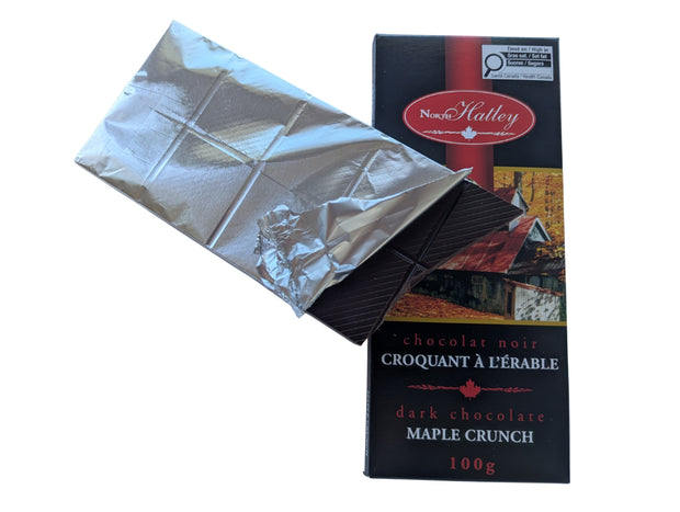 Partially unwrapped Dark Chocolate Maple Crunch bar showing the dark chocolate squares inside the silver wrapper beside the package. A Canadian-made dark chocolate maple treat featuring maple sugar.