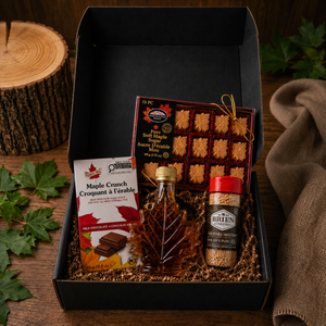 LOONMOON Core Maple Box with Canadian maple treats including maple syrup leaf bottle, soft maple sugar candies, maple sugar shaker, and Maple Crunch Belgian milk chocolate arranged in a black gift box on a rustic wooden table
