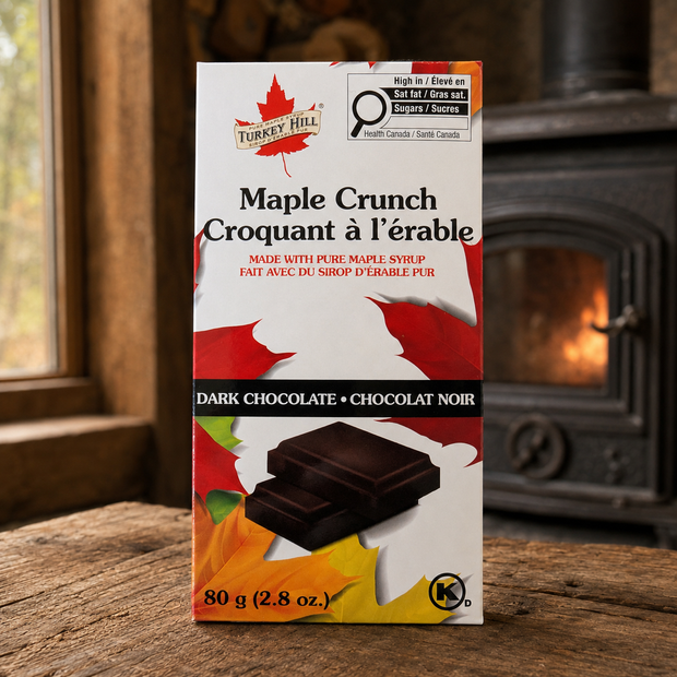Maple Crunch dark chocolate bar on a rustic wooden table with a wood stove in the background.