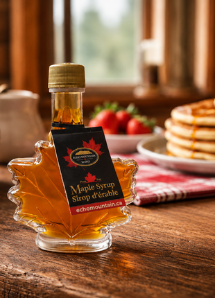 Rustic Canadian maple syrup leaf bottle on a wooden breakfast table with pancakes and strawberries in a cozy cabin kitchen setting.