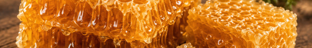 Golden honeycomb pieces on rustic wood, showing the natural wax structure behind pure beeswax candles.