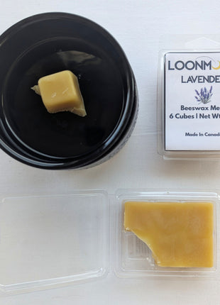 LOONMOON Lavender beeswax melts shown beside a black wax warmer with one wax cube in the dish and the open clamshell revealing the wax inside.  This product image combines packaging, wax texture, and a simple in-use setup to help customers visualize the lavender beeswax melts.