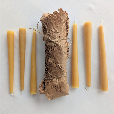 Six natural beeswax taper candles arranged around their honeycomb-paper-wrapped bundle on a soft white background.  This complete six-candle set shows the warm golden beeswax colour, natural surface variation, cotton wicks and low-plastic kraft-paper presentation used for the LOONMOON taper candle package.