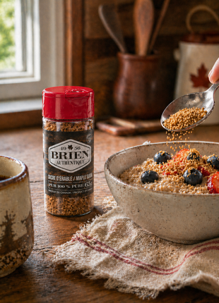 Maple sugar shaker beside a breakfast bowl with berries, coffee, and maple sugar sprinkled over oatmeal.