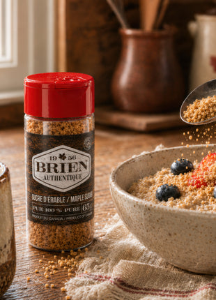 Maple sugar shaker beside a breakfast bowl with berries, coffee, and maple sugar sprinkled over oatmeal.