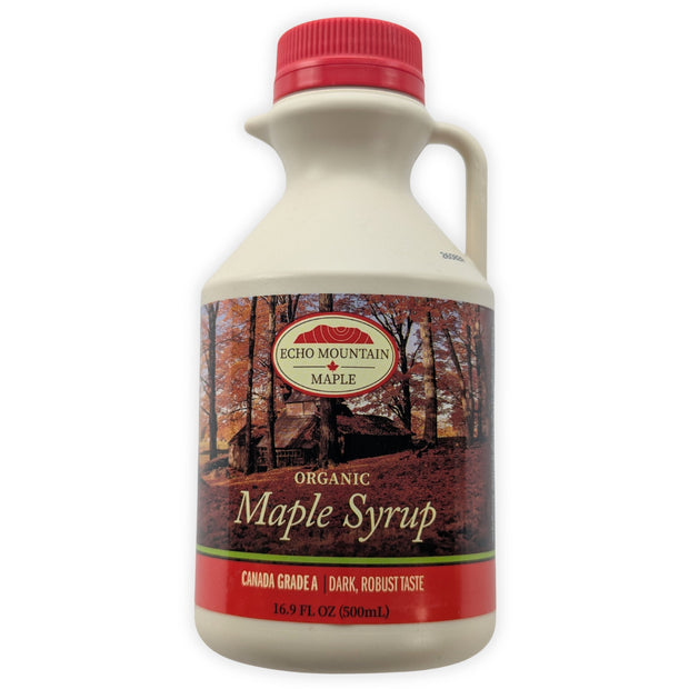 A front view of a 500 mL Echo Mountain organic maple syrup jug on a clean white background.  The cream-coloured jug has a red cap, built-in handle and pouring spout, with an autumn sugar-bush label identifying the syrup as Canada Grade A, dark with a robust taste.