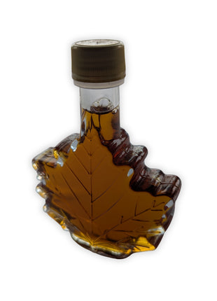 Angled view of pure Canadian maple syrup in a decorative maple leaf glass bottle, showcasing the iconic Canadian bottle design and rich amber colour.  Premium maple syrup made in Canada for breakfast, baking, desserts, and Canadian gift giving.