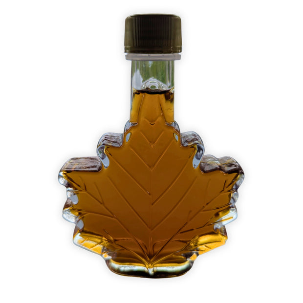 Pure Canadian maple syrup in a traditional maple leaf glass bottle displayed on a clean white background.  Authentic amber maple syrup made in Canada, perfect for pancakes, waffles, baking, gifts, and anyone looking for genuine Canadian maple syrup.