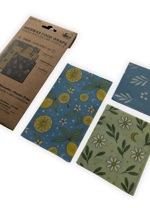 Angled product display of the LOONMOON reusable beeswax food wraps package with all three included wraps arranged beside it on a clean white background.  Sustainable food storage wraps made in Canada from natural materials that combine attractive botanical designs with long-lasting everyday kitchen performance.