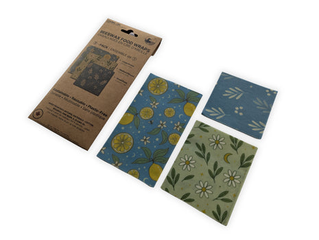 Angled product display of the LOONMOON reusable beeswax food wraps package with all three included wraps arranged beside it on a clean white background.  Sustainable food storage wraps made in Canada from natural materials that combine attractive botanical designs with long-lasting everyday kitchen performance.