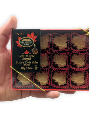 Hand holding a 15-piece soft maple sugar candy gift box made in Canada to demonstrate package size and presentation.  Individually wrapped maple leaf candies crafted from pure Canadian maple syrup in a premium gift box perfect for souvenirs, gifts and Canadian treats.