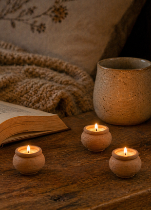 Beeswax tealights beside an open book and mug in a cozy reading nook